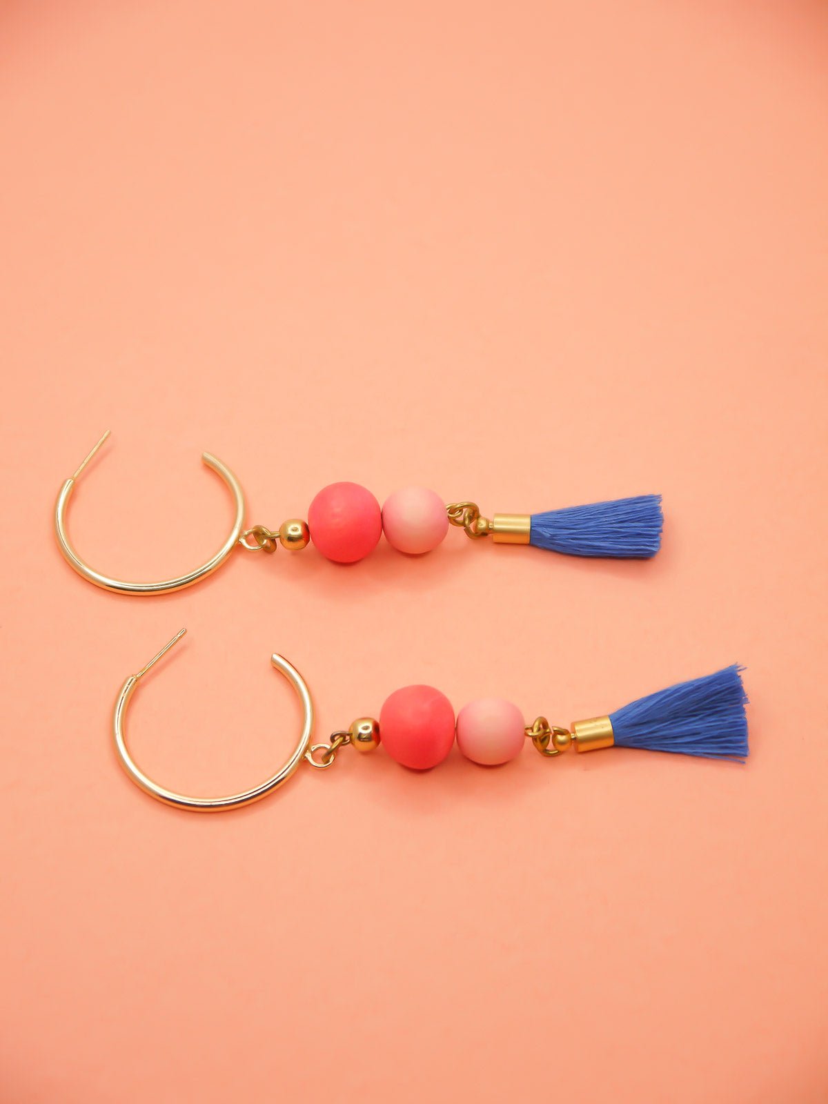 Gold hoop beaded tassel dangle earrings with wooden beads in salmon and pink paired with a sapphire blue tassel and gold hoops