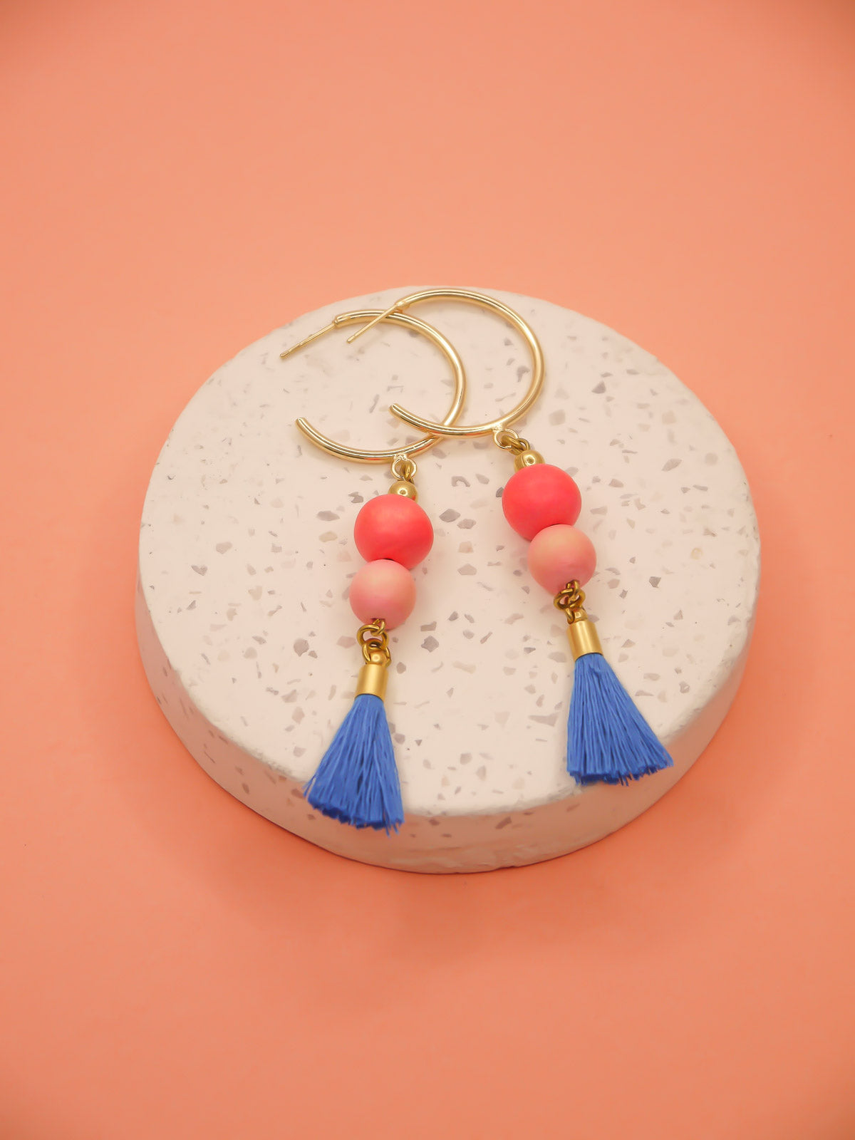 Gold hoop beaded tassel dangle earrings with wooden beads in salmon and pink paired with a sapphire blue tassel and gold hoops