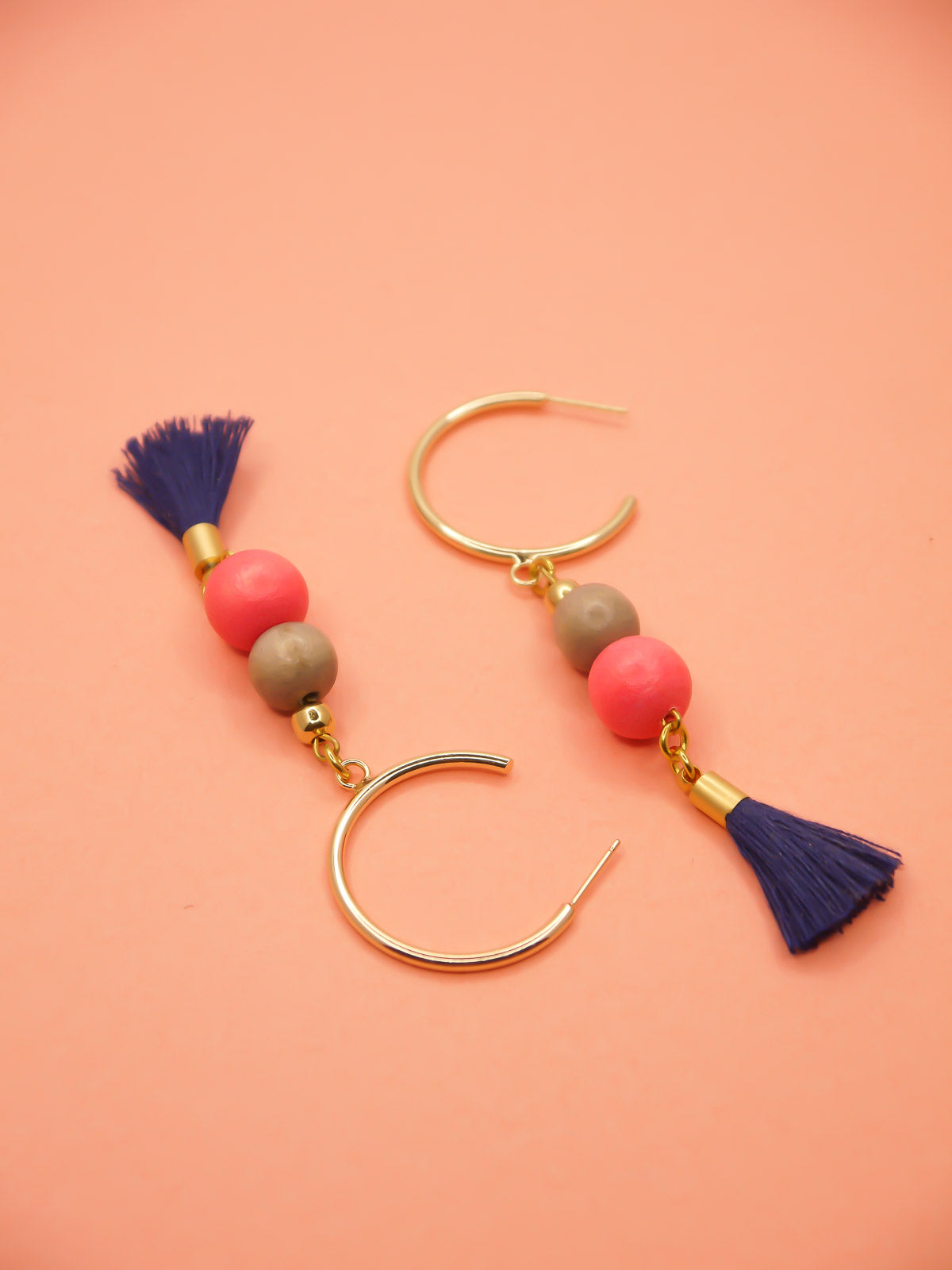 Gold hoop beaded tassel earrings with wooden beads in salmon and light grey with a navy blue tassel and gold hoops