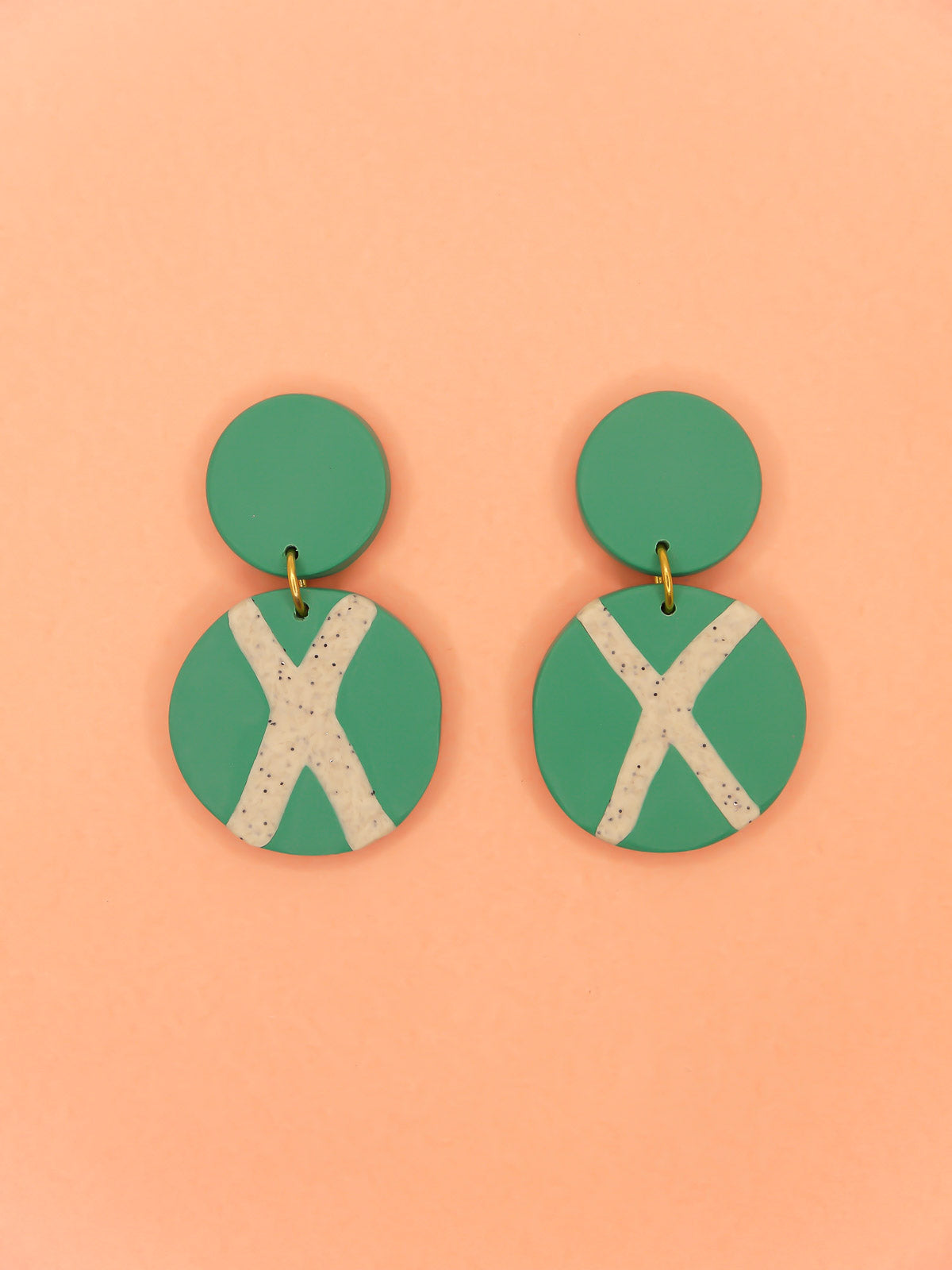 Polymer clay dangle statement earrings with a green stud connected to a green circle with a granite cross in the centre