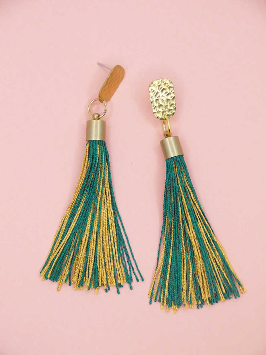 Tassel earrings with green and gold tassels and a textured brass stud on a pink background