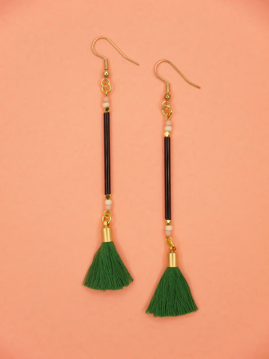 Long delicate bead stick dangle earrings with black glass tube beads & contrasting seed beads in pink & white. Paired with a green cotton tassel & hung from gold plated nickel free ear wires