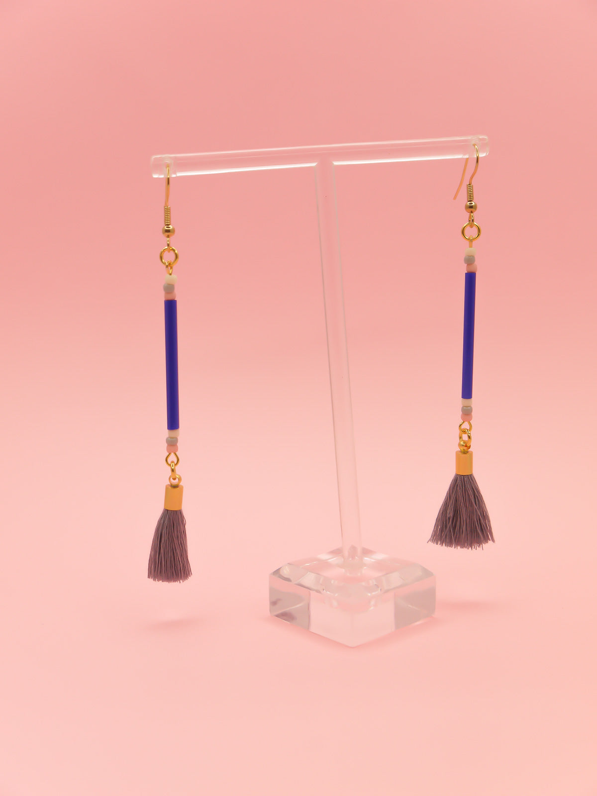 Long delicate bead stick dangle earrings featuring blue tube beads with contrasting seed beads in pink, white & grey, paired with a grey cotton tassel & hung from gold plated nickel free ear wires