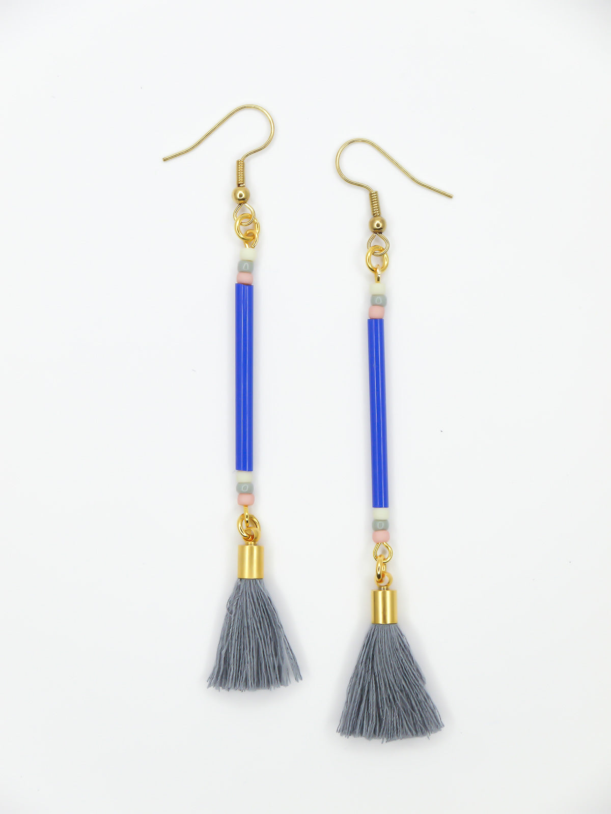 Long delicate bead stick dangle earrings featuring blue tube beads with contrasting seed beads in pink, white & grey, paired with a grey cotton tassel & hung from gold plated nickel free ear wires