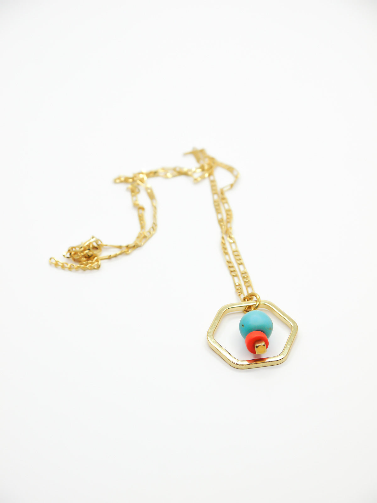 Geometric necklace comprising of a gold plated hexagon charm with a turquoise gemstone bead in the centre with an orange ceramic and brass square bead. Hung from a 24k shiny gold faceted curb chain with extender