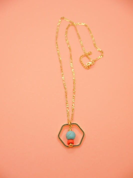 Geometric necklace comprising of a gold plated hexagon charm with a turquoise gemstone bead in the centre with an orange ceramic and brass square bead. Hung from a 24k shiny gold faceted curb chain with extender