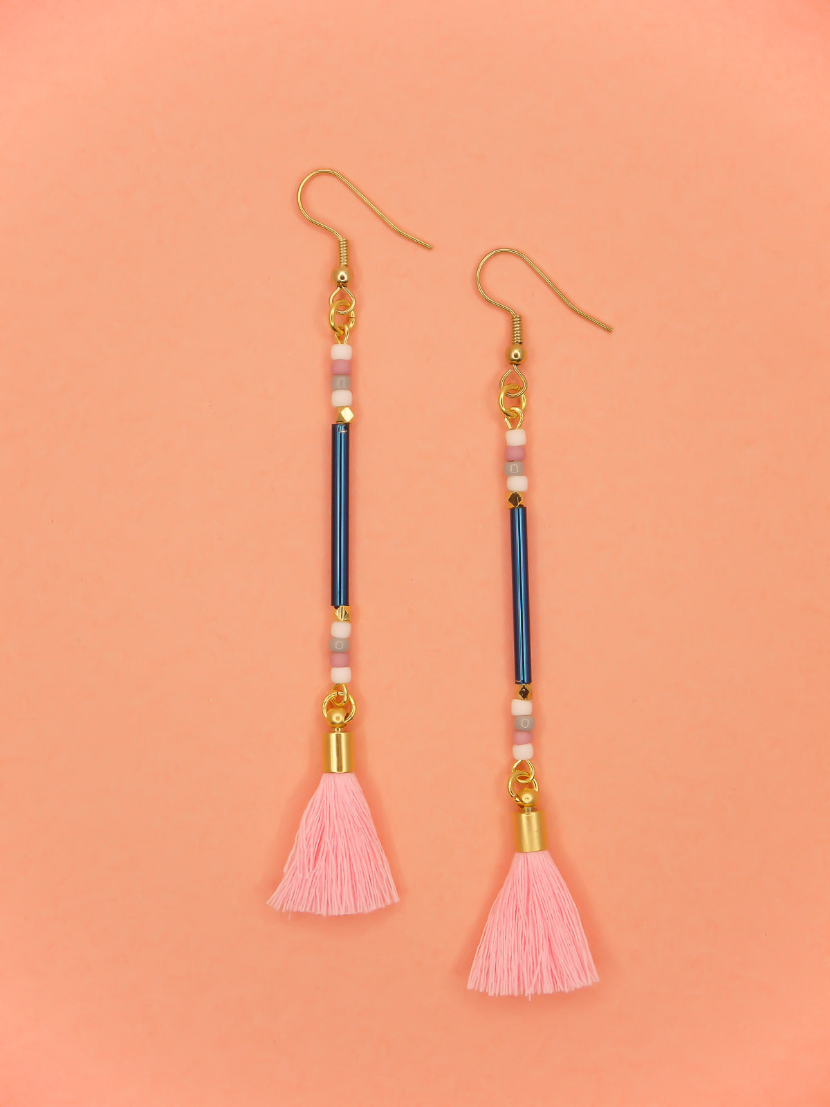 Long beaded tassel earrings with blue glass tube beads and white, pink & grey seed beads with a light pink cotton tassel and hung from gold plated nickel free ear wires