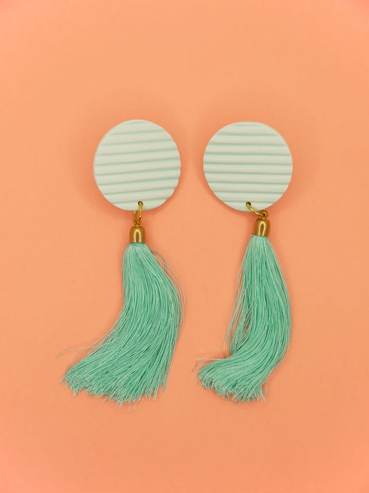 Long mint tassel dangle earrings with a fluted textured striped mint disk stud made out of polymer clay with a long mint silky tassel with a brass end cap and stainless steel posts