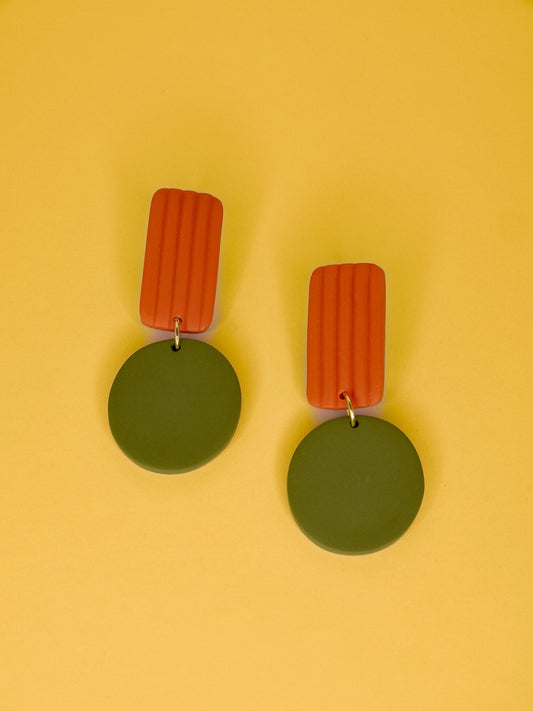 Pair of geometric earrings with green round pendants and orange rectangular striped tops on a yellow background