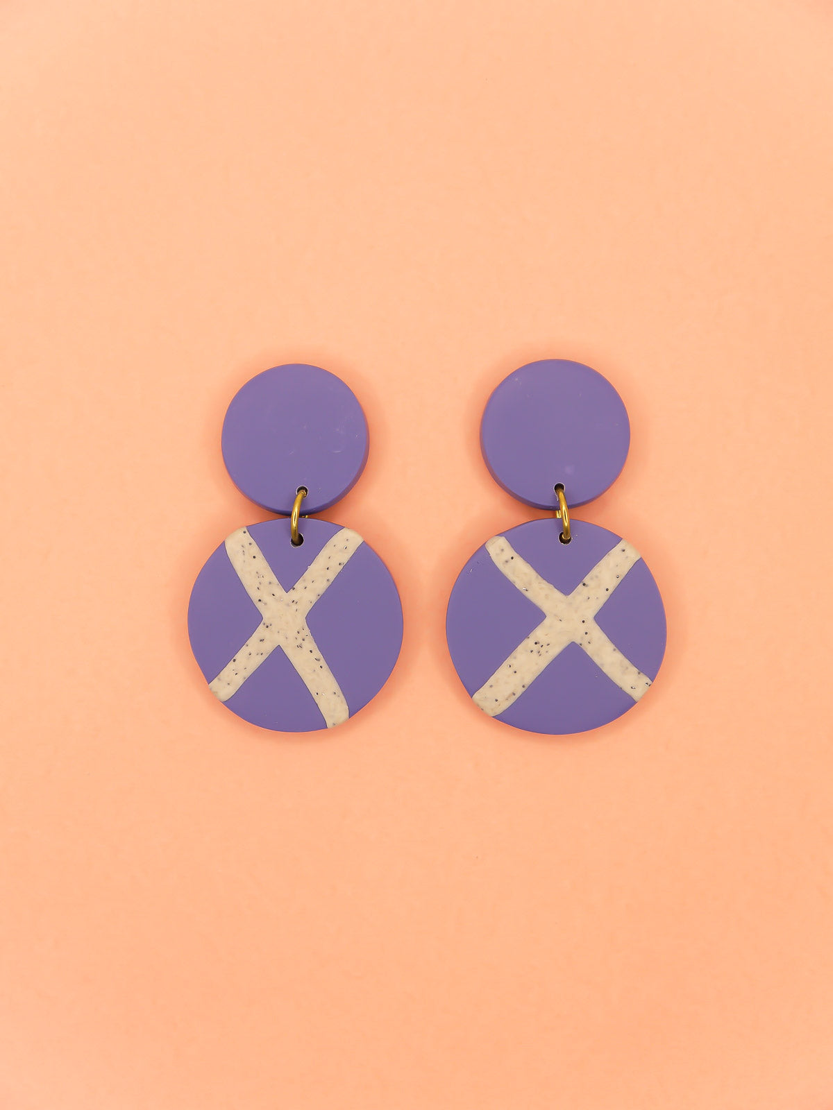 Polymer clay dangle statement earrings with a periwinkle blue stud connected to a periwinkle blue circle with a granite cross in the centre