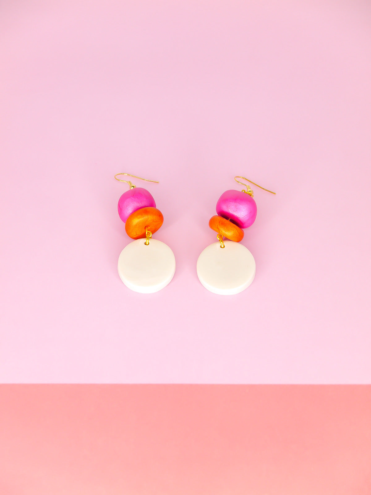 Lightweight metallic beaded dangle earrings with a pearl circle, topped with hand rolled metallic beads in pink and rust, hung from gold plated ear wires