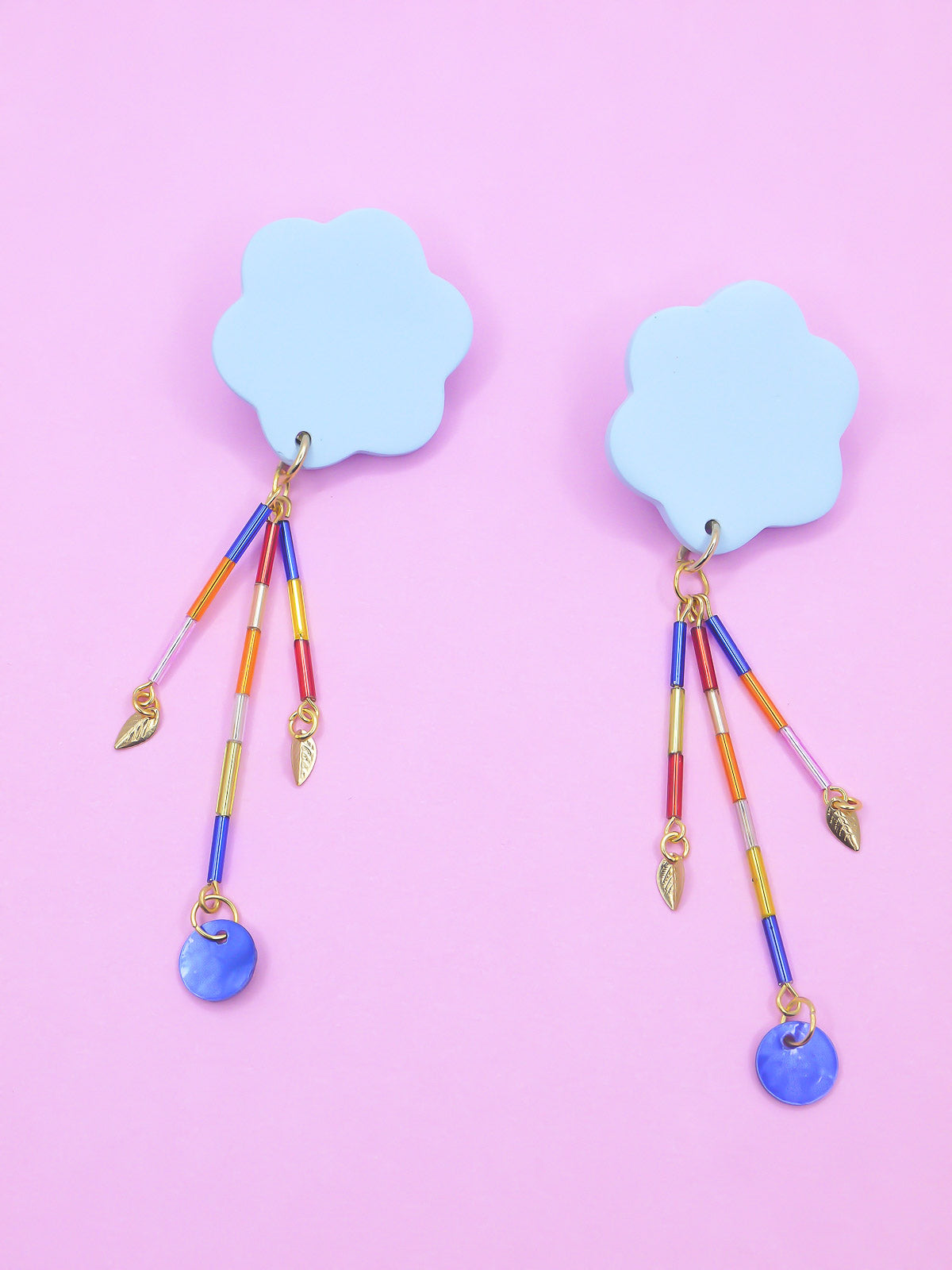 Colourful earrings of blue clouds with glass dangle tube beads on a pink background