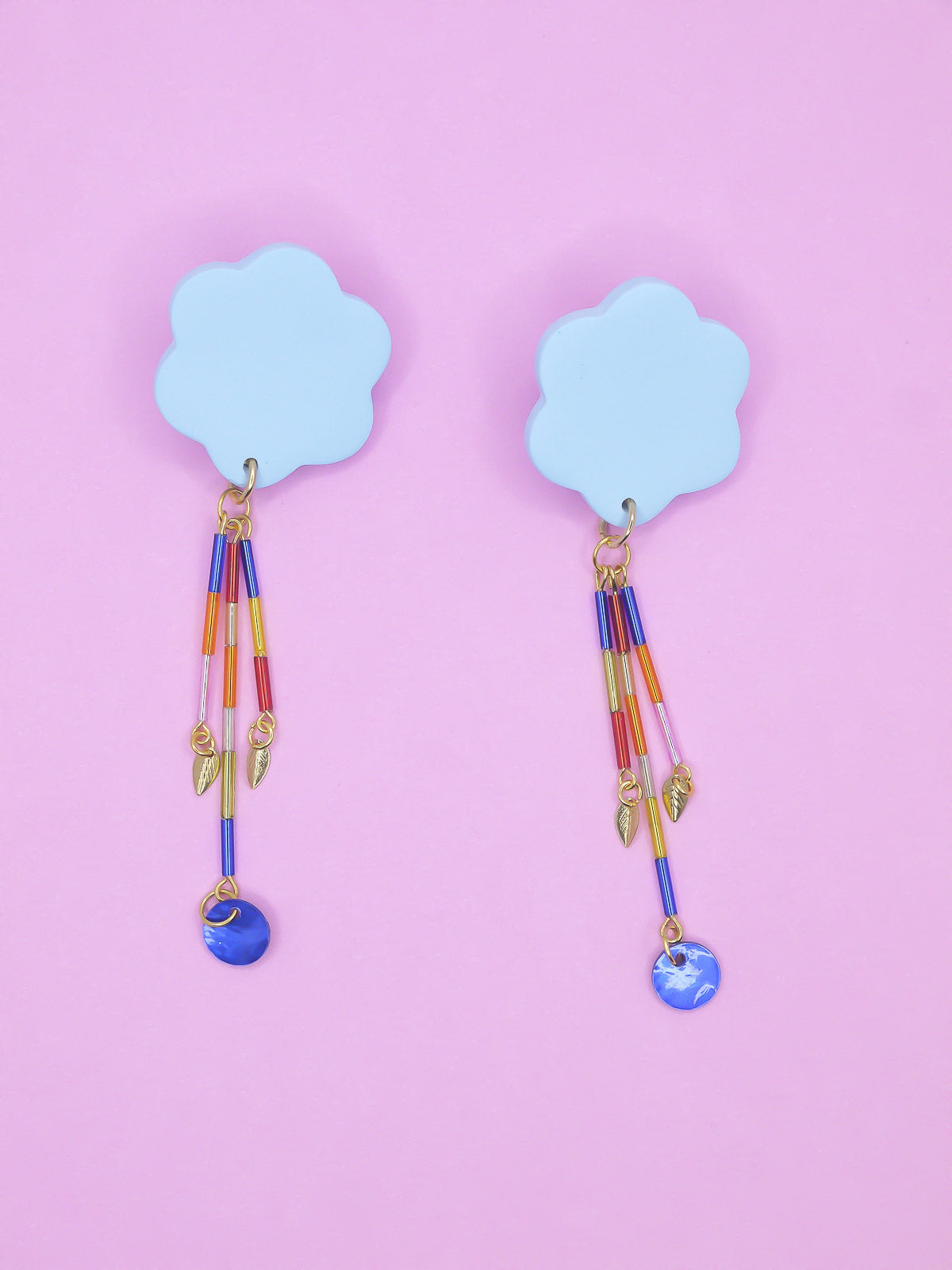 Colourful earrings of blue clouds with glass dangle tube beads on a pink background