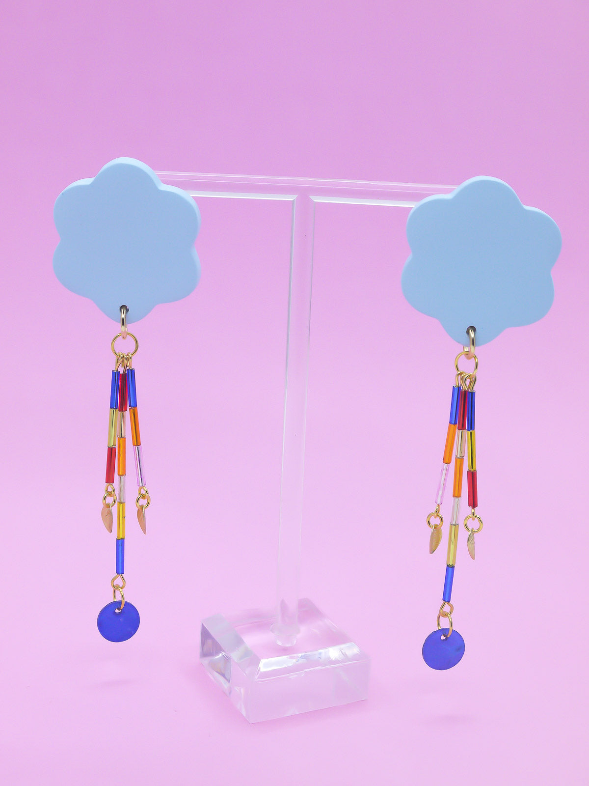 Colourful earrings of blue clouds with glass dangle tube beads on a pink background