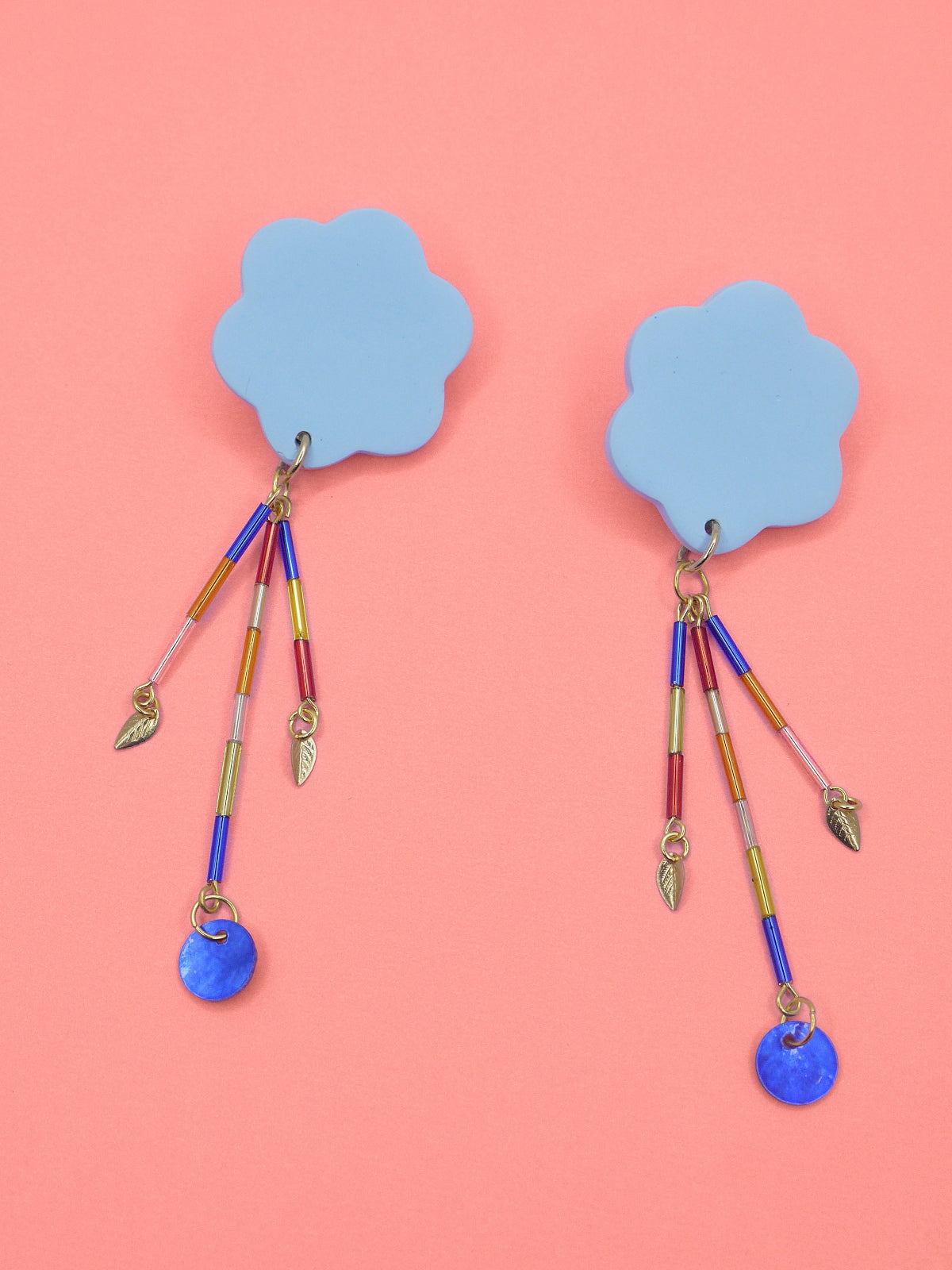 Colourful earrings of blue clouds with glass dangle tube beads on a pink background