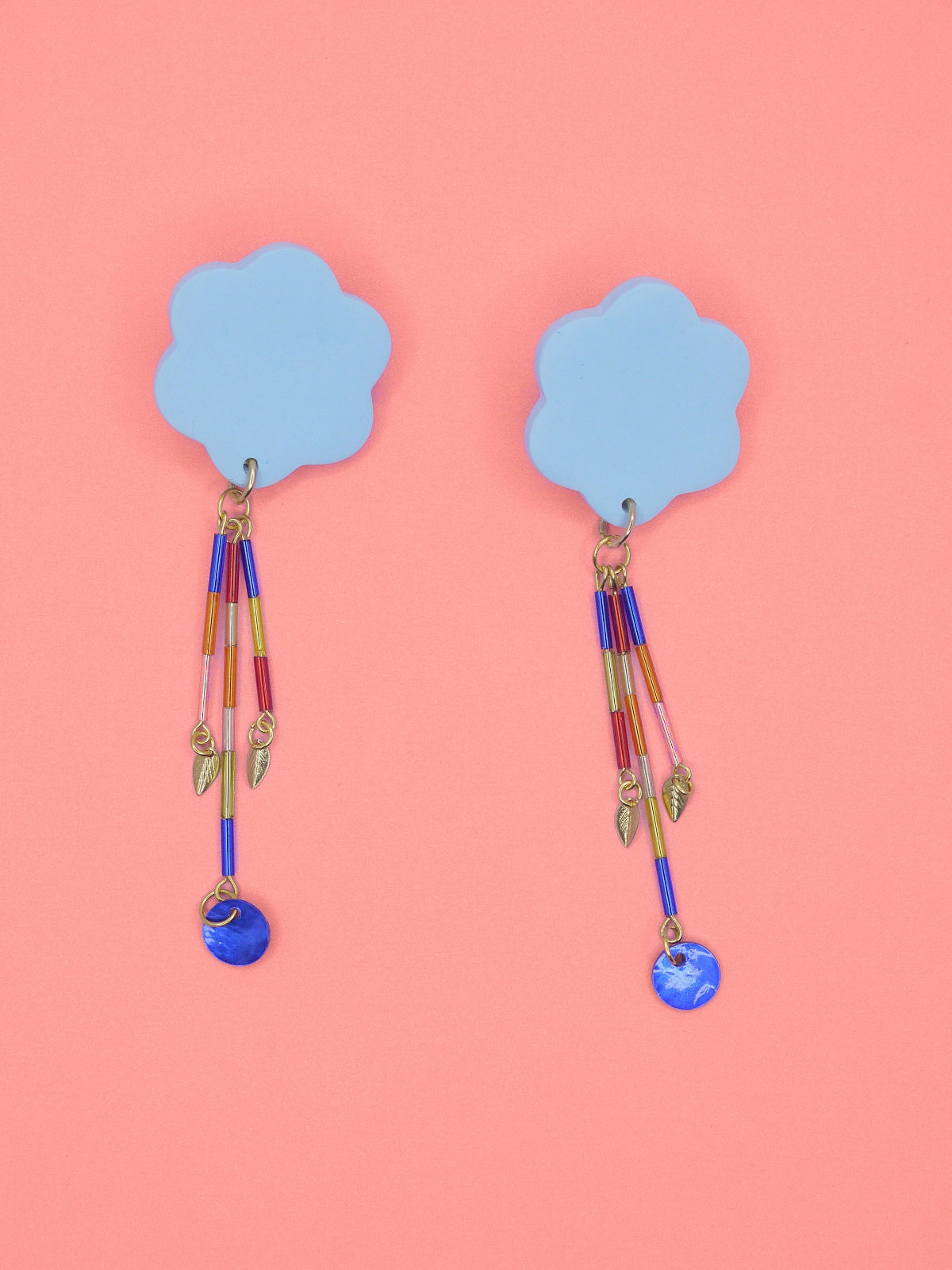 Colourful earrings of blue clouds with glass dangle tube beads on a pink background