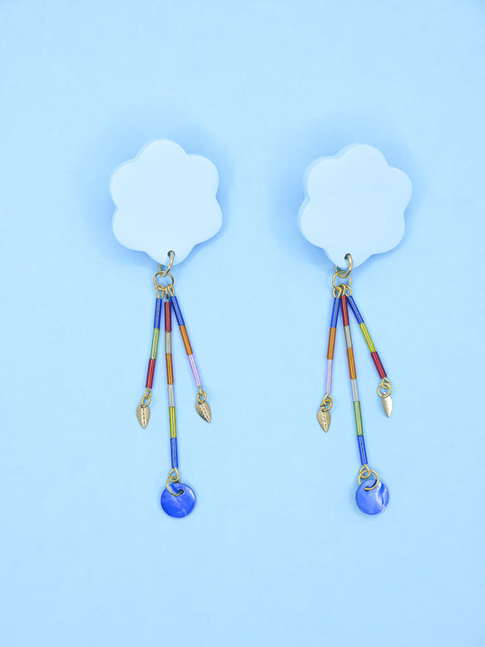 Colourful earrings of blue clouds with glass dangle tube beads on a pink background