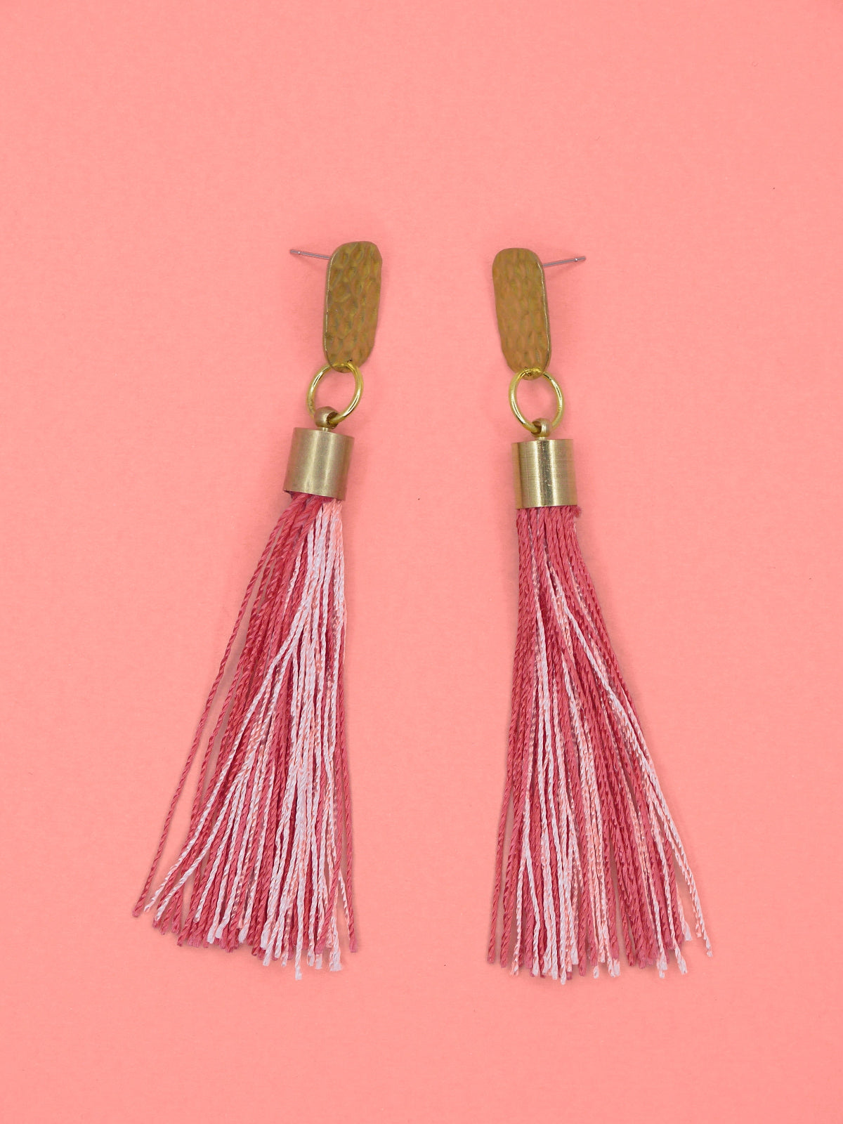 Pink & red tassel earrings with textured brass studs on a pink background
