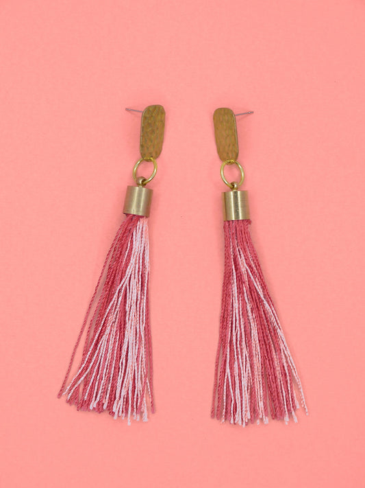 Pink & red tassel earrings with textured brass studs on a pink background
