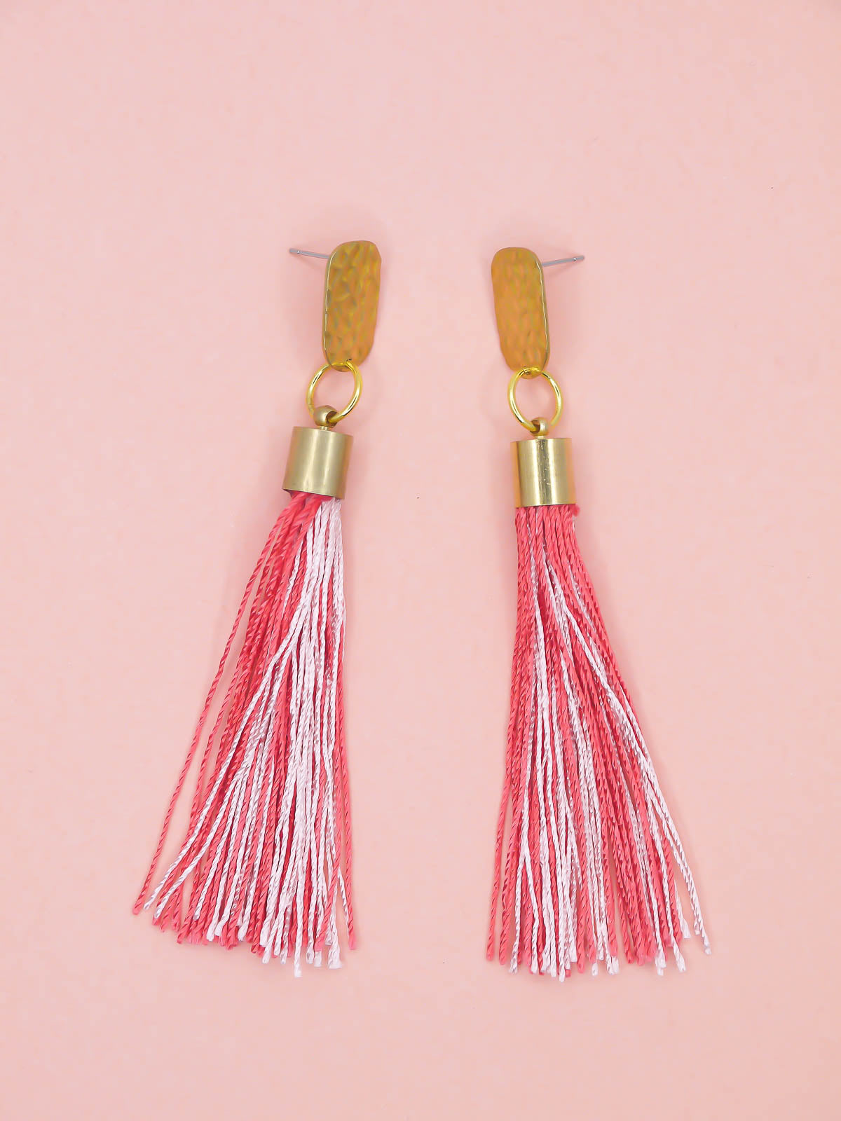 Pink & red tassel earrings with textured brass studs on a pink background