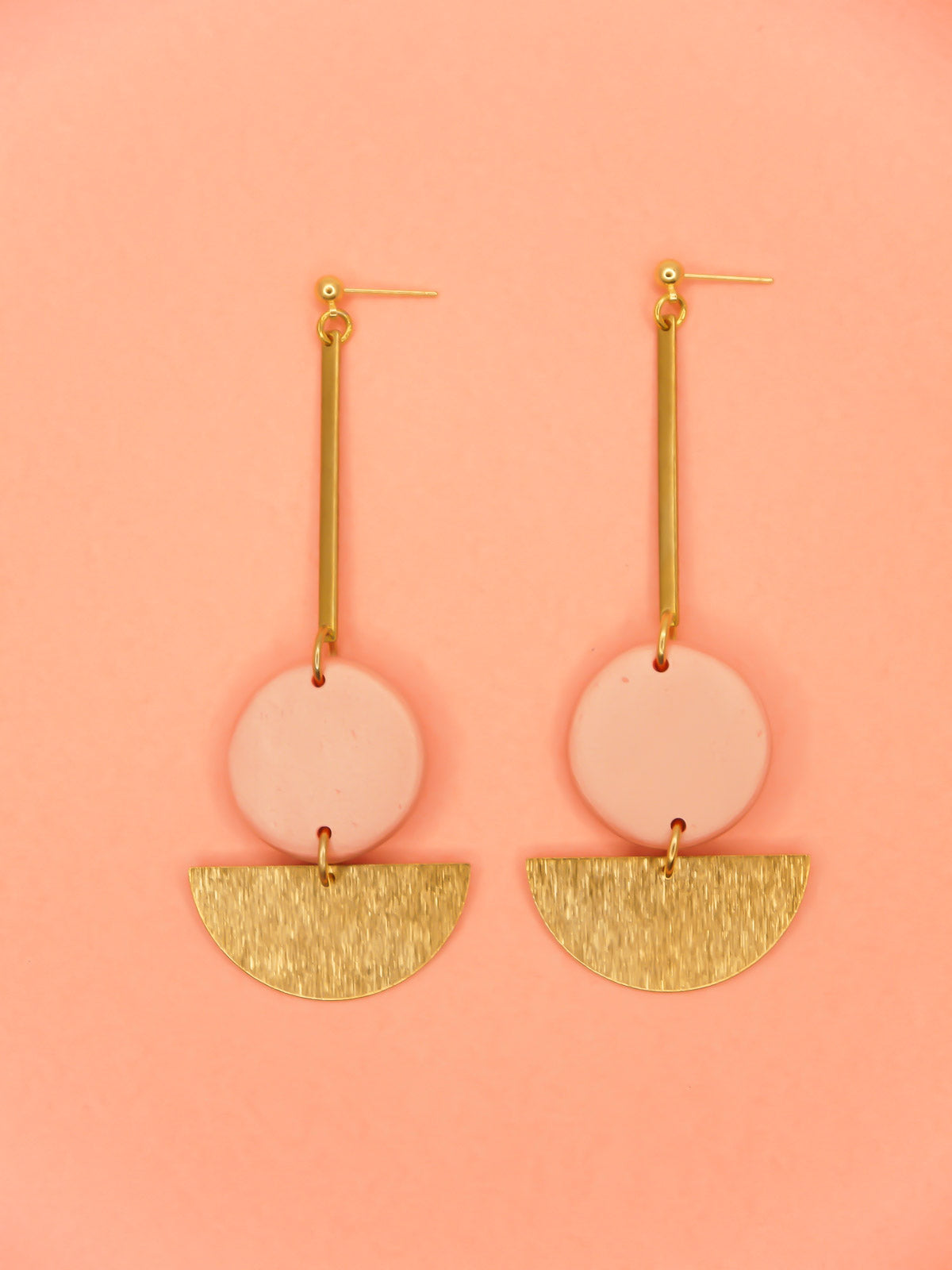 Dangle geometric statement earrings with a gold plated ball stud, a brass stick with a polymer clay round metallic circle in rose gold connected to a textured brass semi circle