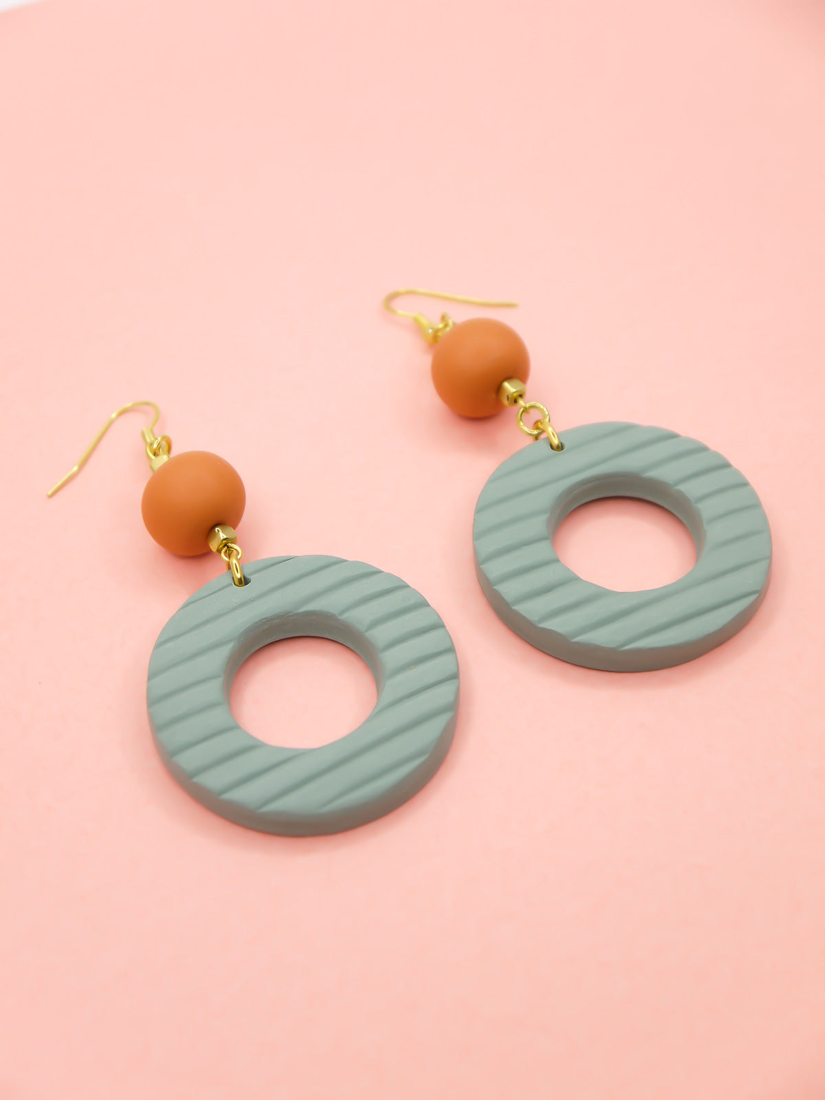 Geometric polymer clay statement dangle earrings with sage striped textured hoops, connected to terracotta ball beads and hung from brass ear wires.