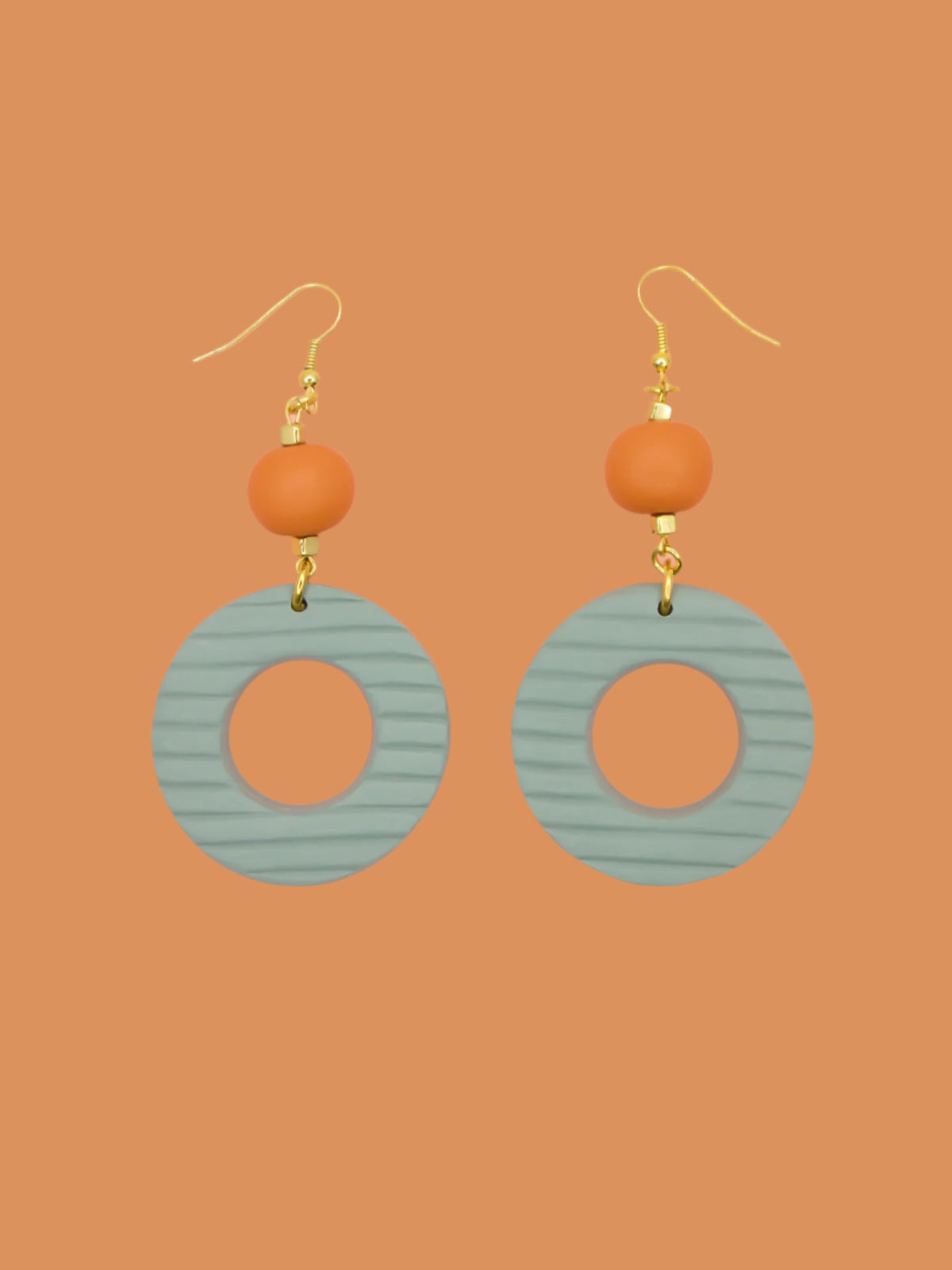 Geometric polymer clay statement dangle earrings with sage striped textured hoops, connected to terracotta ball beads and hung from brass ear wires.