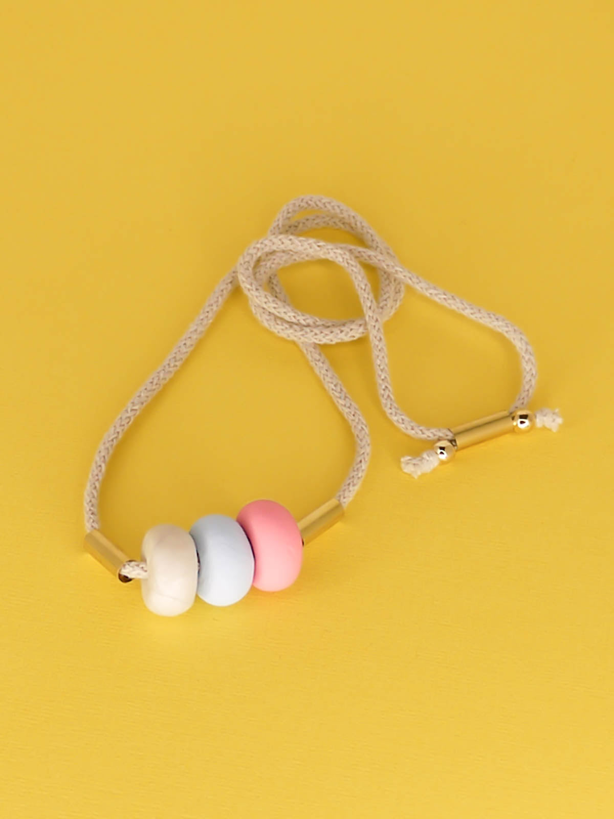 Modern lightweight polymer clay bead necklace comprising of three handmade beads in pink, ice blue and marble with two brass tubes either side strung on an adjustable beige cotton rope to wear short or long.