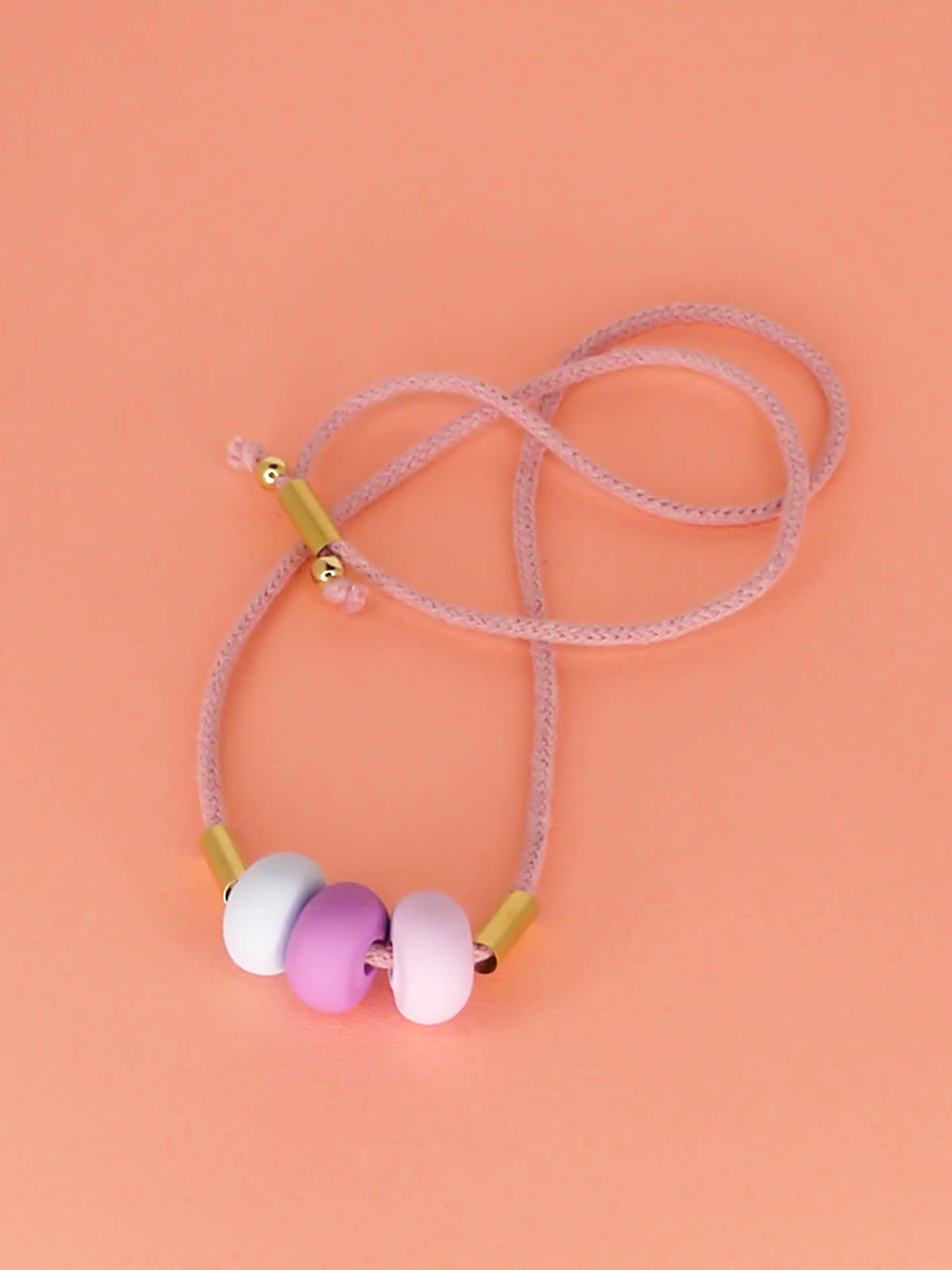 Lightweight statement bead necklace made up of lilac cotton rope which is adjustable so wear it long or short. 3 handmade polymer clay beads in lilac, purple and ice blue with 2 brass tube beads.