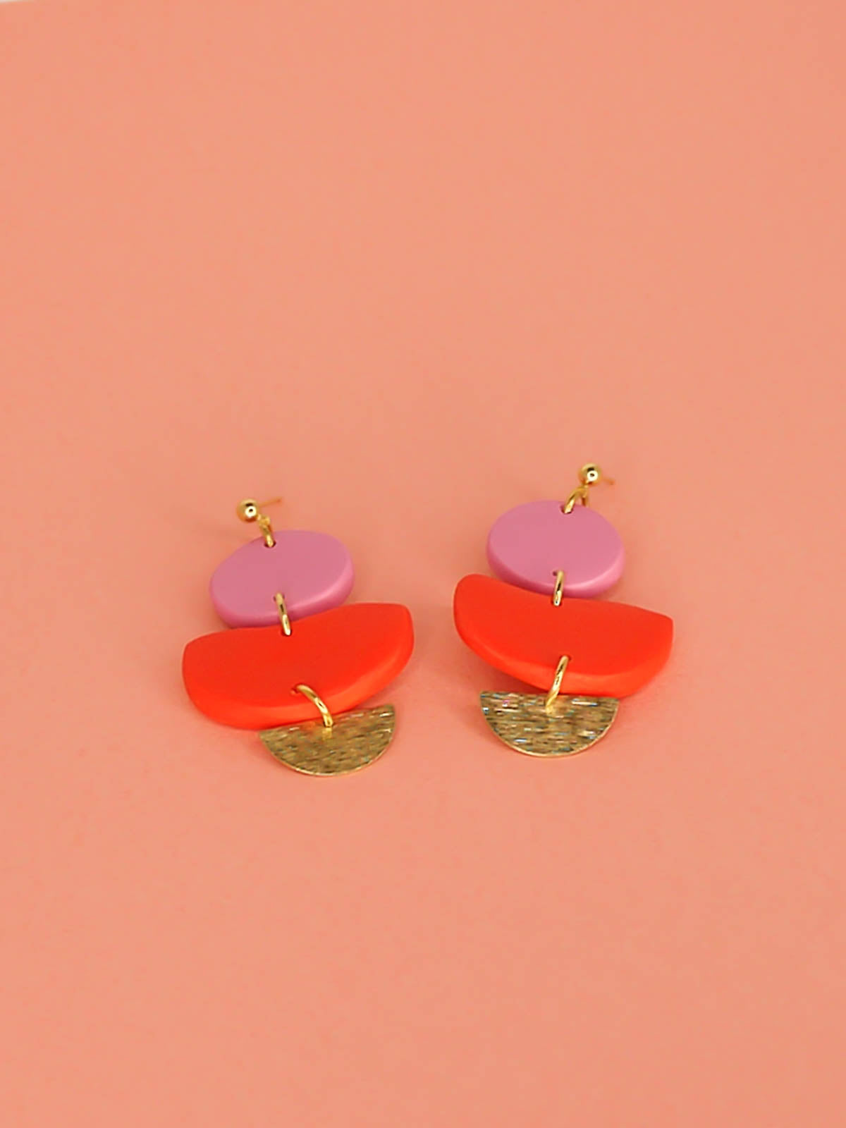 3 tier geometric colour block dangle earrings with gold plated ball studs connected to a fuchsia polymer clay circle & red clay semi circle with a textured brass semi circle charm