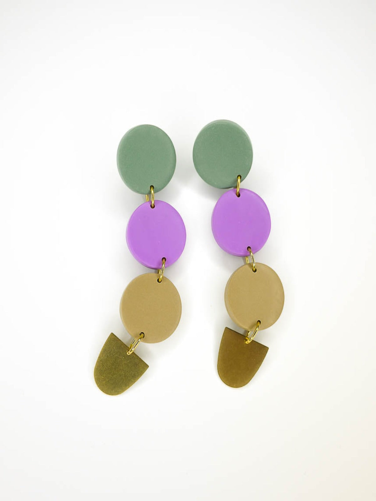 4 tier long colour block circle dangle statement earrings with 3 connected circles made from polymer clay in sage, purple & beige, with a brass semi circle charm dangling on the bottom and stainless steel earring posts.