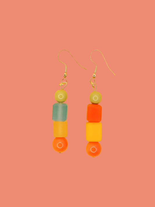 Geometric asymmetrical coloured bead earrings with glass circle beads in orange, square resin beads in orange, yellow and blue , topped with a glass bead in sage green. Hung from brass earring hooks.