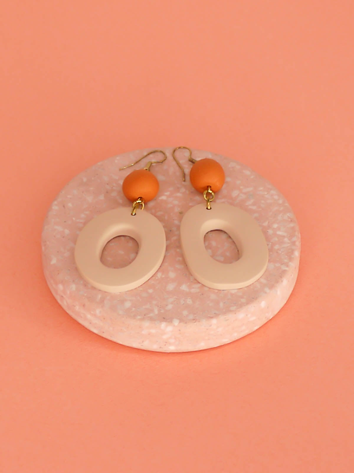 Modern hoop dangle statement earrings with a beige hoop & terracotta bead, hung from brass hooks. Handmade from polymer clay.