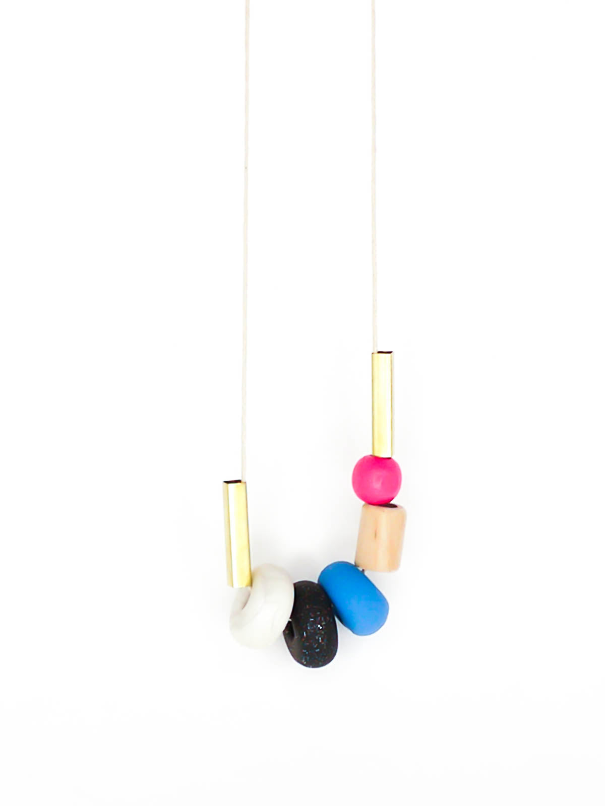 Lightweight geometric colourful bead necklace with 3 handmade polymer clay beads in marble, blue & black glitter- wood tube bead & pink wood bead, brass tube beads on either side, strung on a cotton cord with a blue wood bead knotted at the end