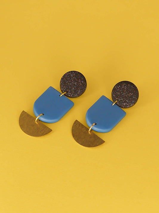 Geometric polymer clay dangle earrings with a black glitter circle stud, connected to a blue arch & a textured brass semi circle 