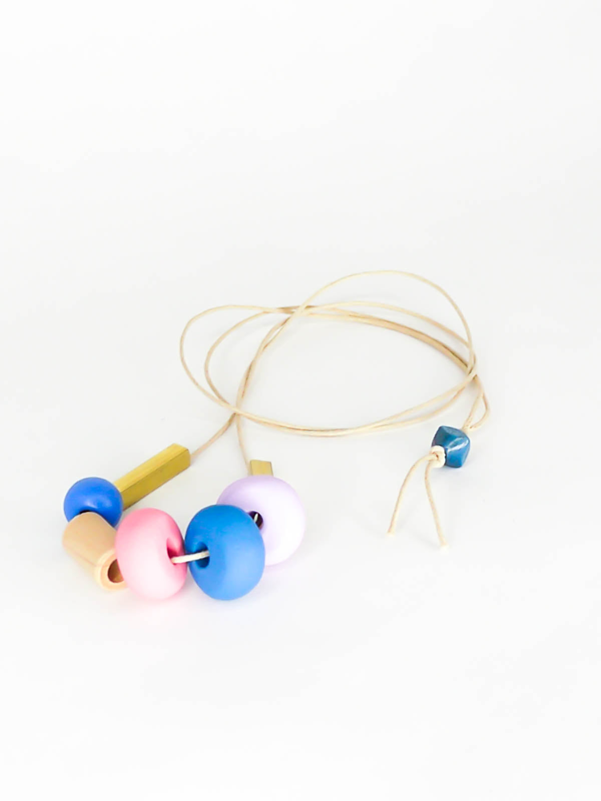 Lightweight geometric colourful bead necklace with 3 handmade polymer clay beads in lilac, blue & pink- wood tube bead & blue wood bead with brass tube beads on either side. Strung on a thin strong cotton cord with a blue wood bead knotted at the end