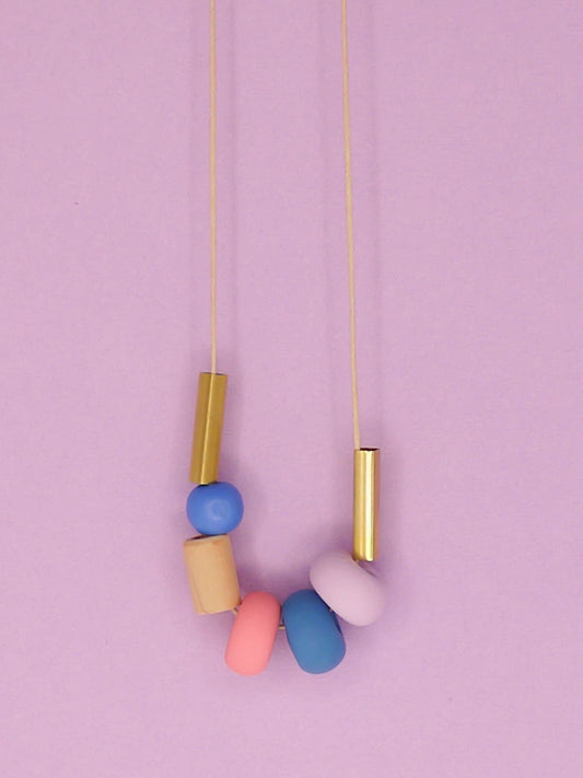 Lightweight geometric colourful bead necklace with 3 handmade polymer clay beads in lilac, blue & pink- wood tube bead & blue wood bead with brass tube beads on either side. Strung on a thin strong cotton cord with a blue wood bead knotted at the end