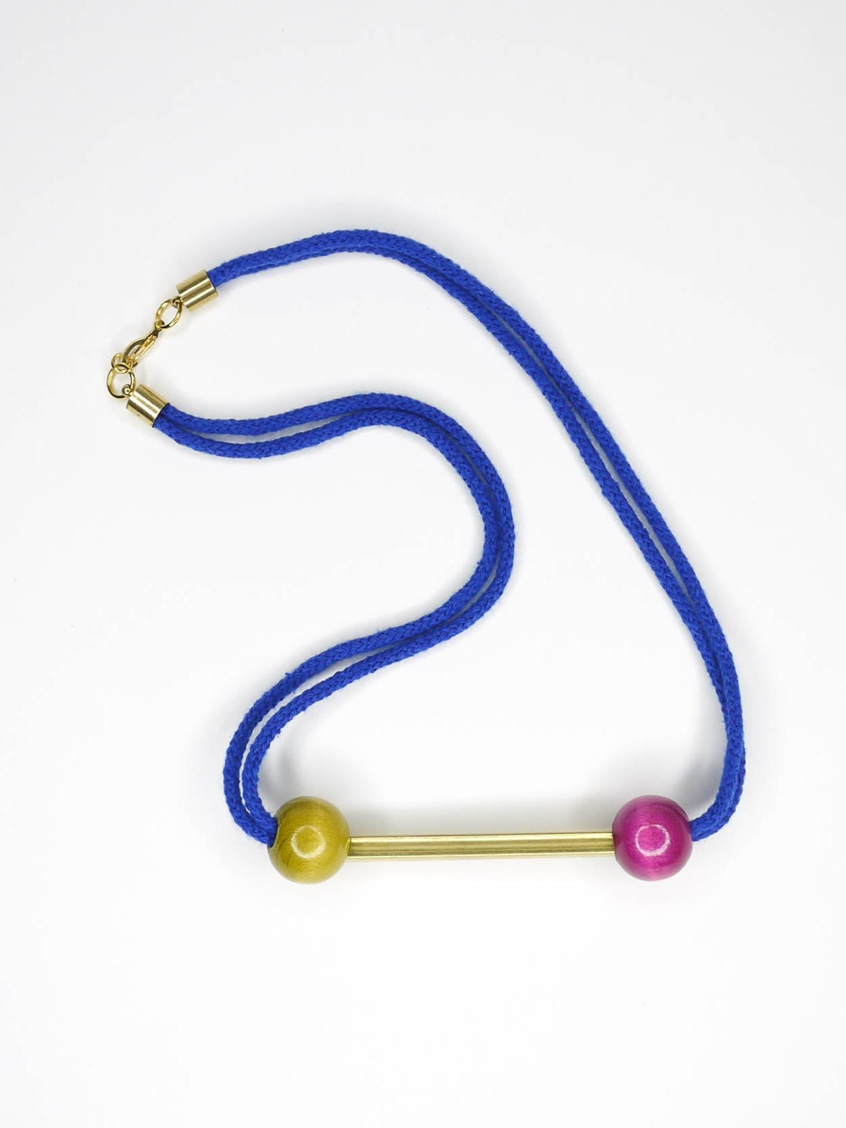 Cobalt blue rope bar necklace with a brass bar with contrasting wooden beads in pink and green with a brass clasp closure