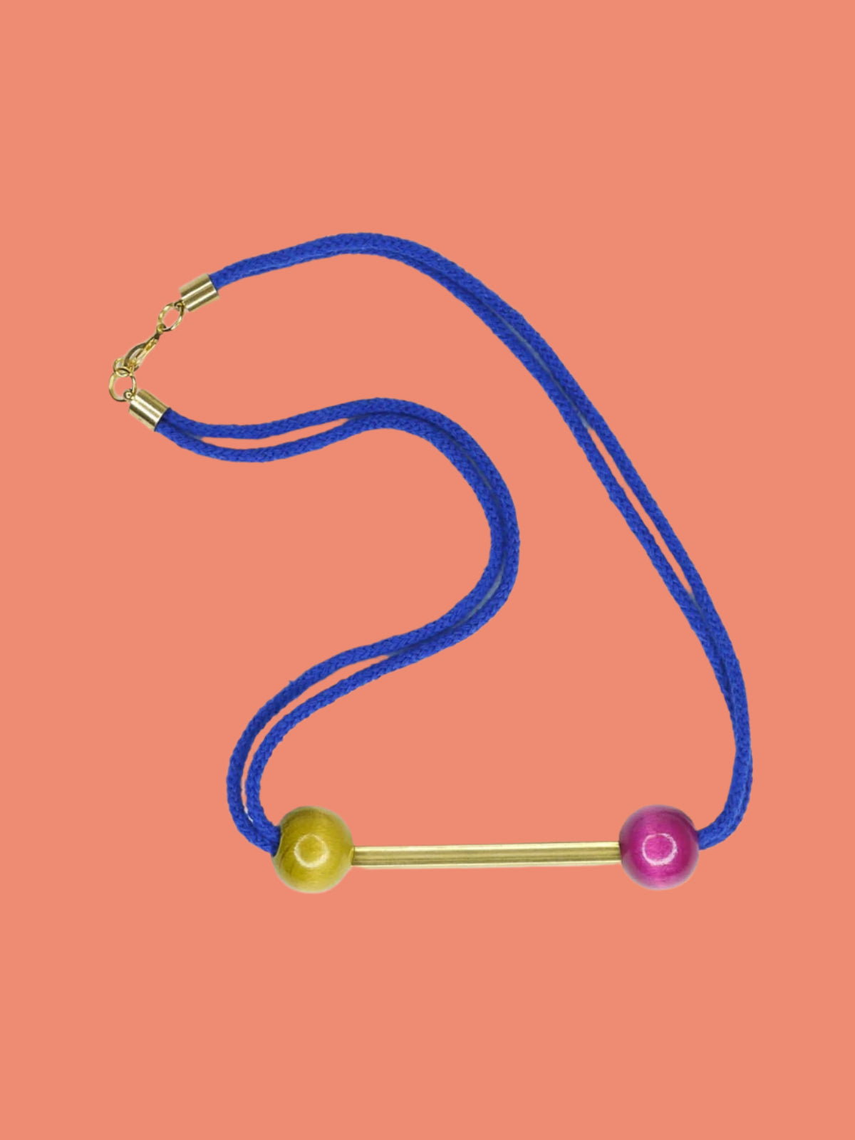 Cobalt blue rope bar necklace with a brass bar with contrasting wooden beads in pink and green with a brass clasp closure