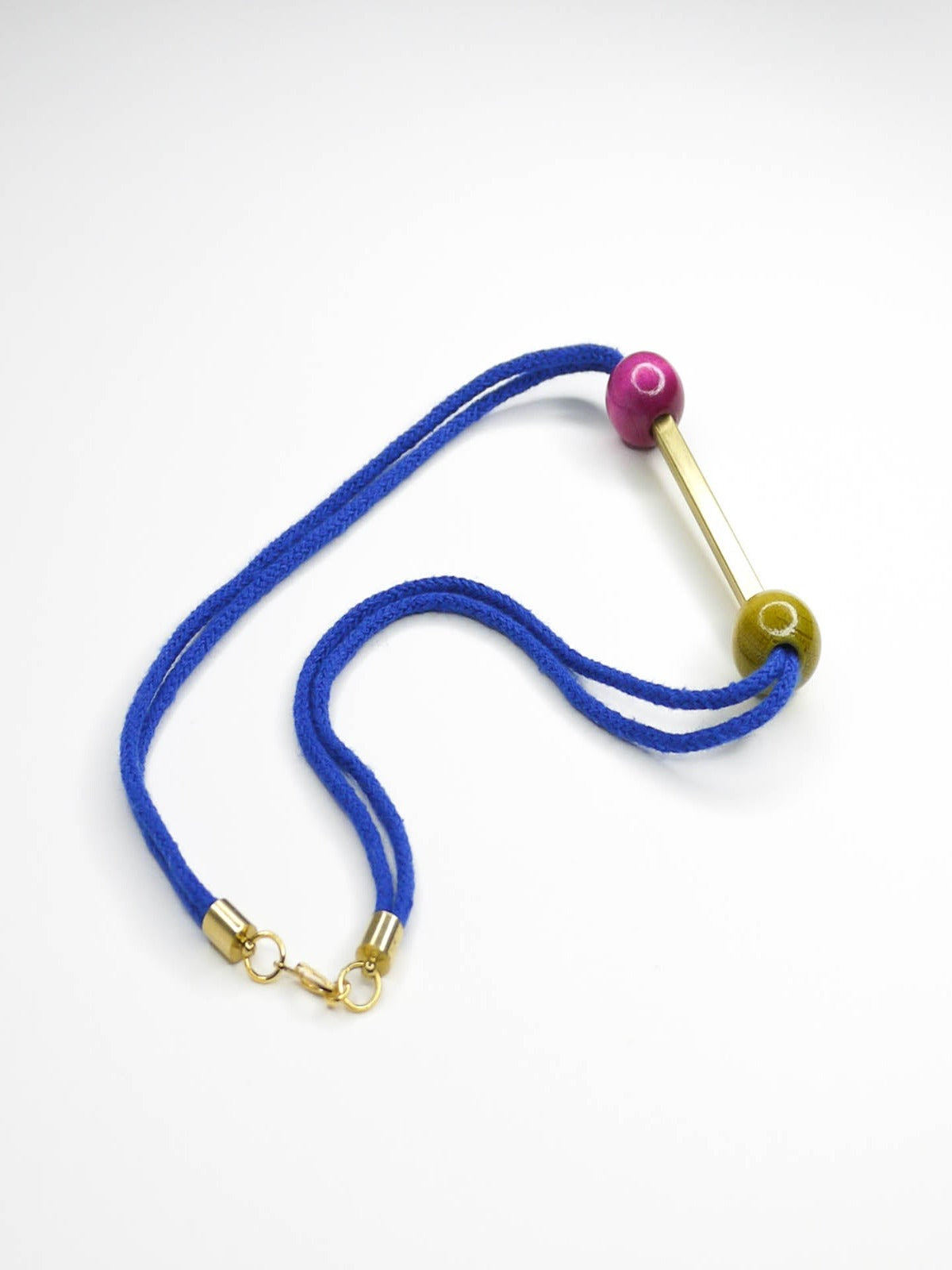 Cobalt blue rope bar necklace with a brass bar with contrasting wooden beads in pink and green with a brass clasp closure