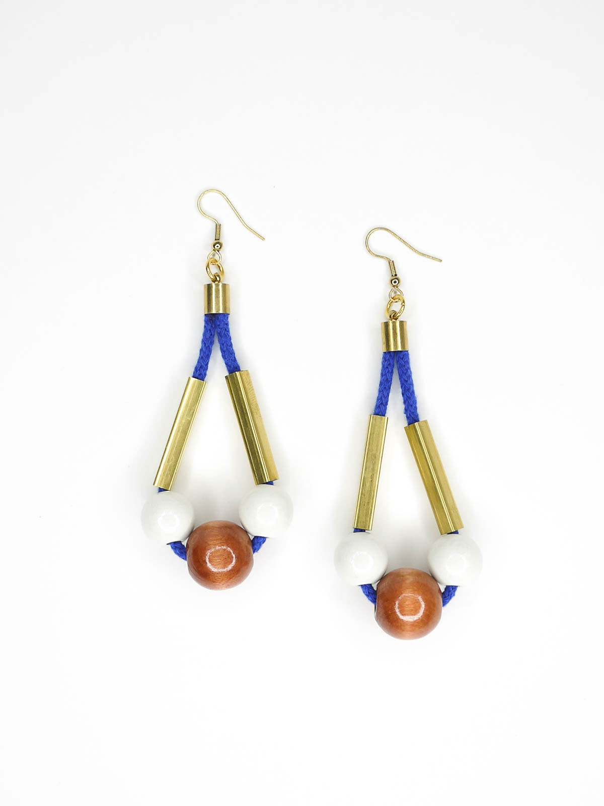 Long bead dangle statement earrings with wooden beads in white & brown & brass tube beads strung on cobalt blue cotton rope with brass end caps, hung from gold plated brass earring hooks.