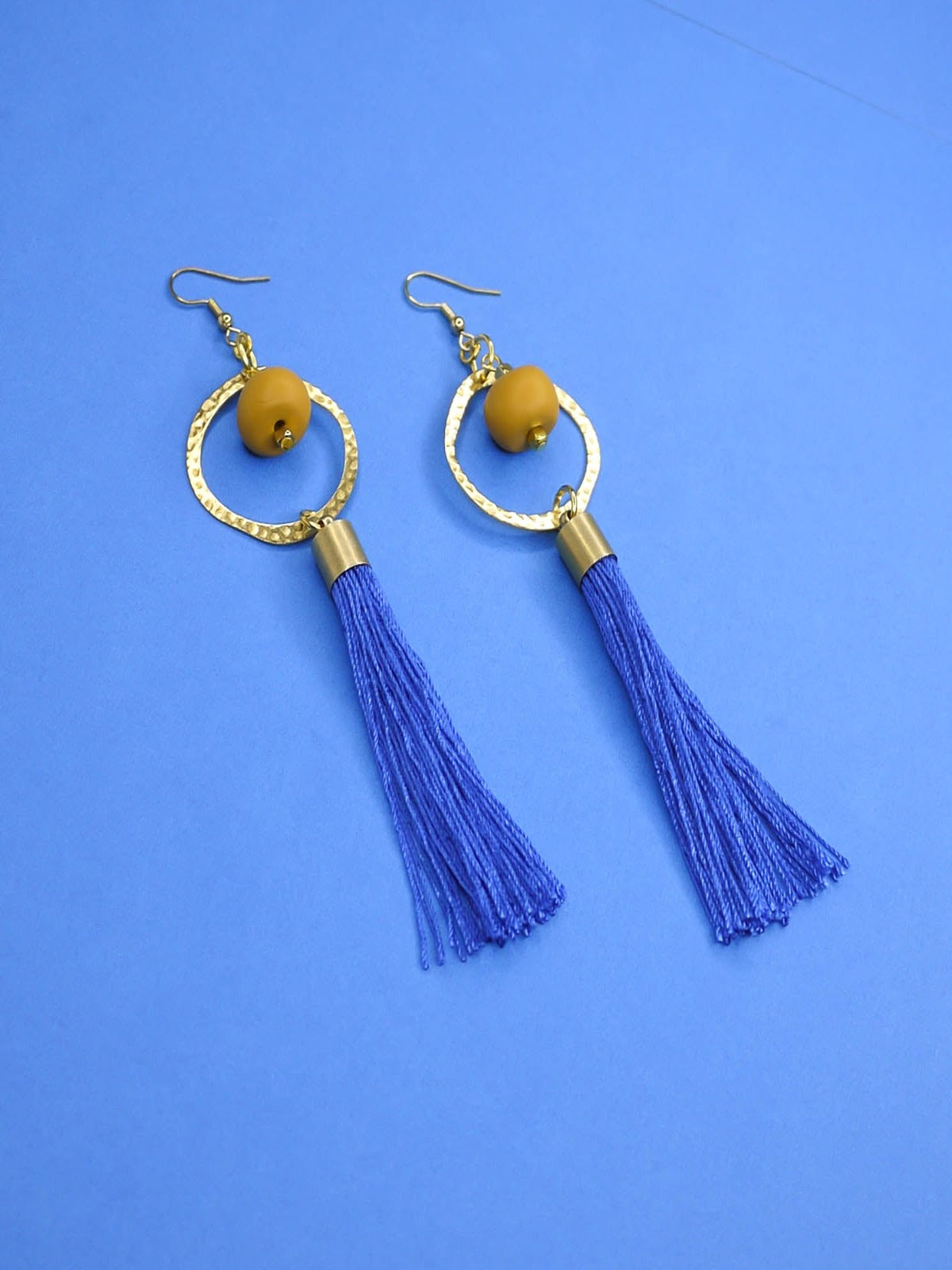 Long tassel statement earrings with gold plated ear wires, connected to a textured brass hoop with a mustard polymer clay bead dangling in the centre & a cobalt blue long tassel hung from the hoop