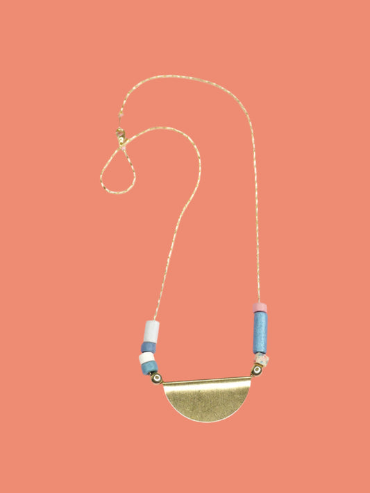 Lightweight & delicate ceramic beaded necklace with a brass semi circle pendant in the centre with ceramic tube beads on either side in pink, blues, white & silver, strung on a thin gold plated snake chain.