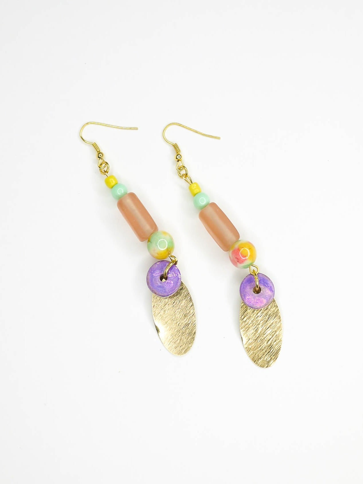 Colourful beaded brass dangle statement earrings with glass and ceramic beads and a textured brass charm, hung from gold plated ear wires