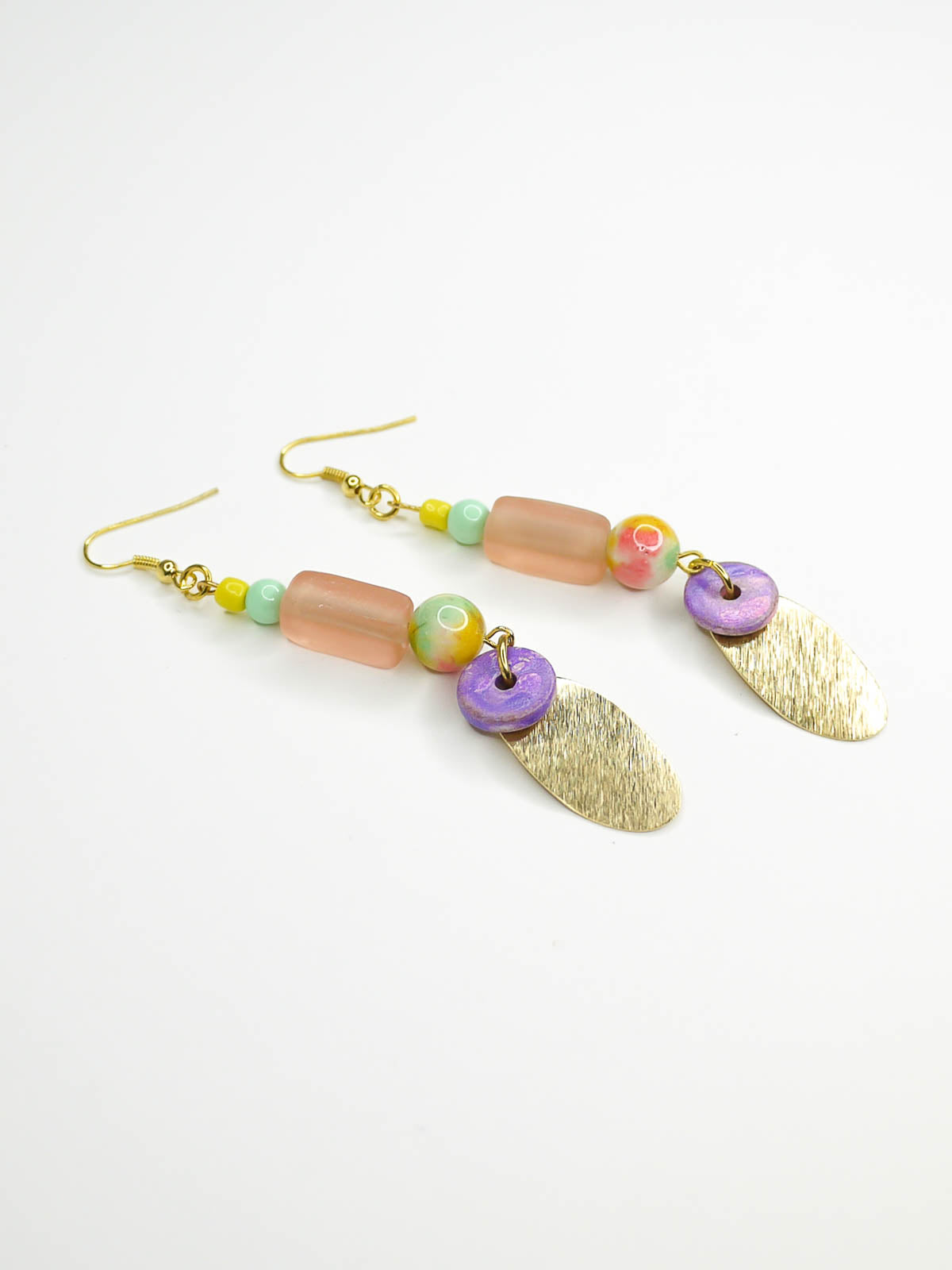 Colourful beaded brass dangle statement earrings with glass and ceramic beads and a textured brass charm, hung from gold plated ear wires