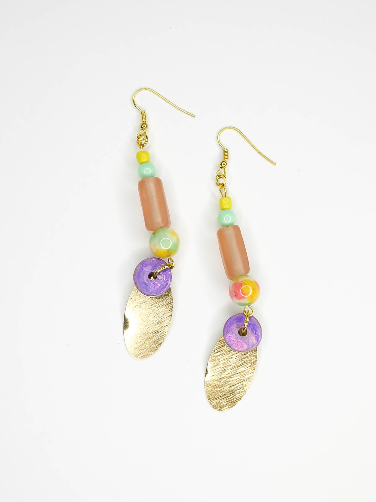 Colourful beaded brass dangle statement earrings with glass and ceramic beads and a textured brass charm, hung from gold plated ear wires