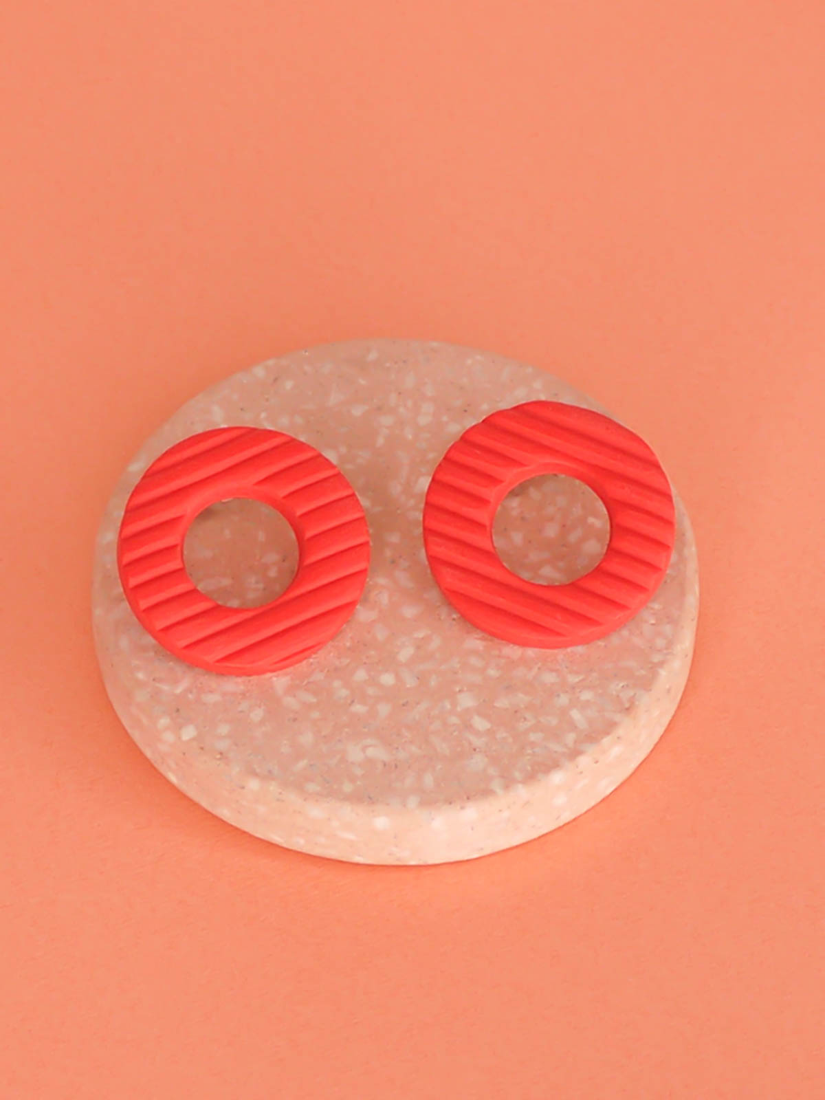 Coral hoop stud statement earrings made out of polymer clay with a fluted striped texture and stainless steel posts