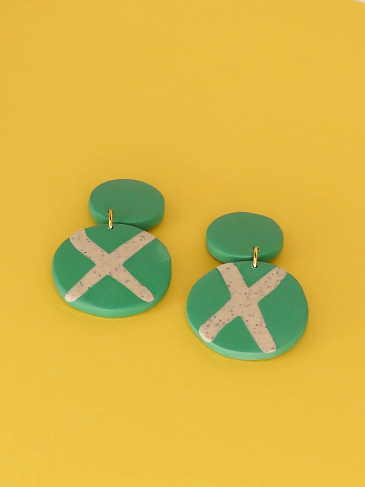 Polymer clay dangle statement earrings with a green stud connected to a green circle with a granite cross in the centre