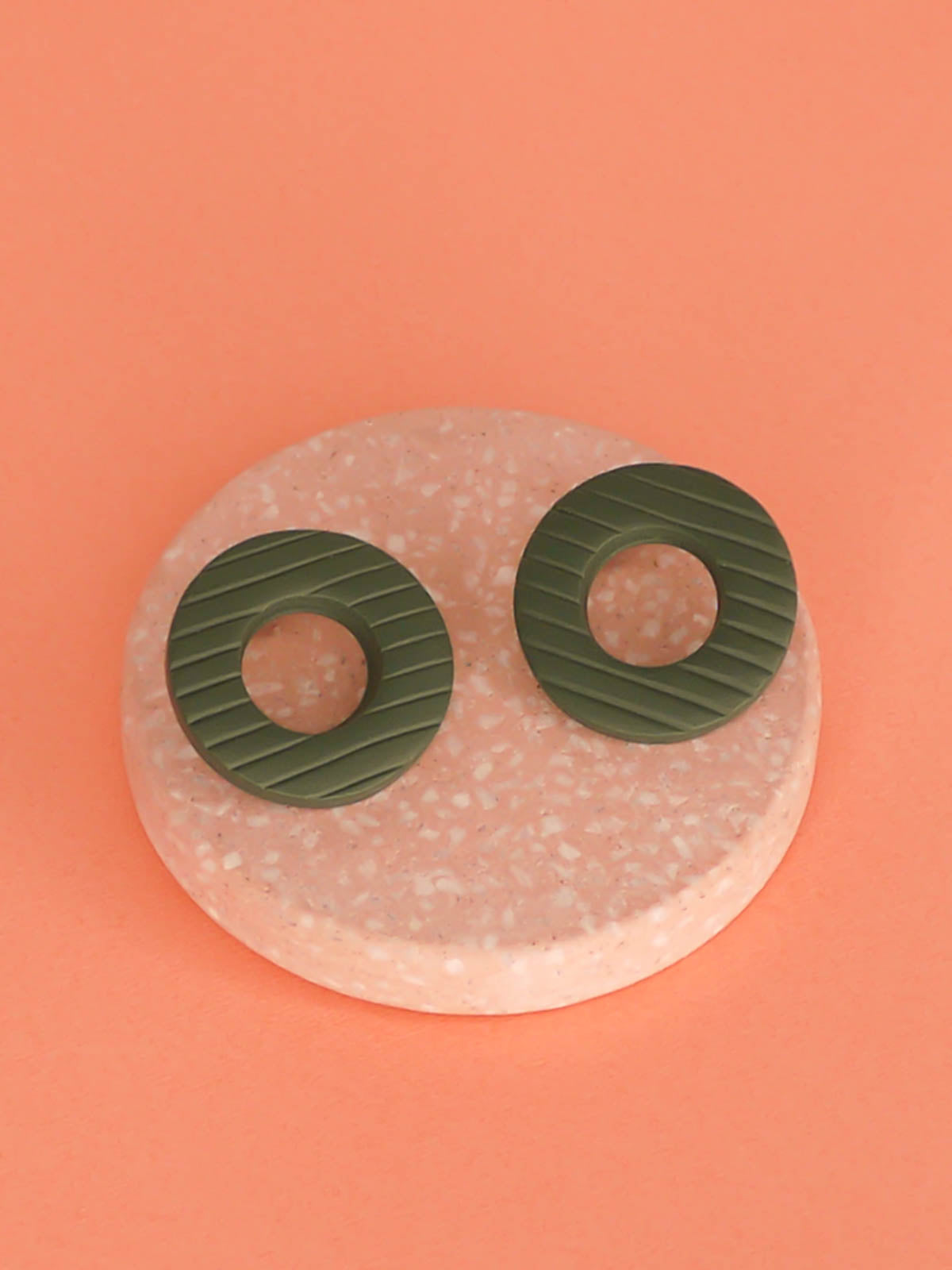 Green hoop stud earrings made out of polymer clay with a striped texture