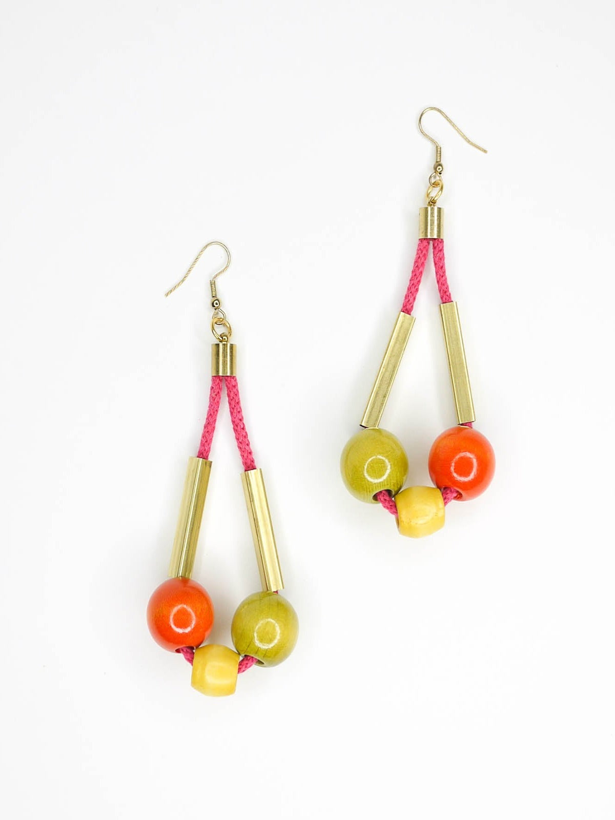 Long bead dangle statement earrings with wooden beads in green, orange & yellow & brass tube beads strung on hot pink cotton rope with brass end caps, hung from gold plated brass earring hooks.